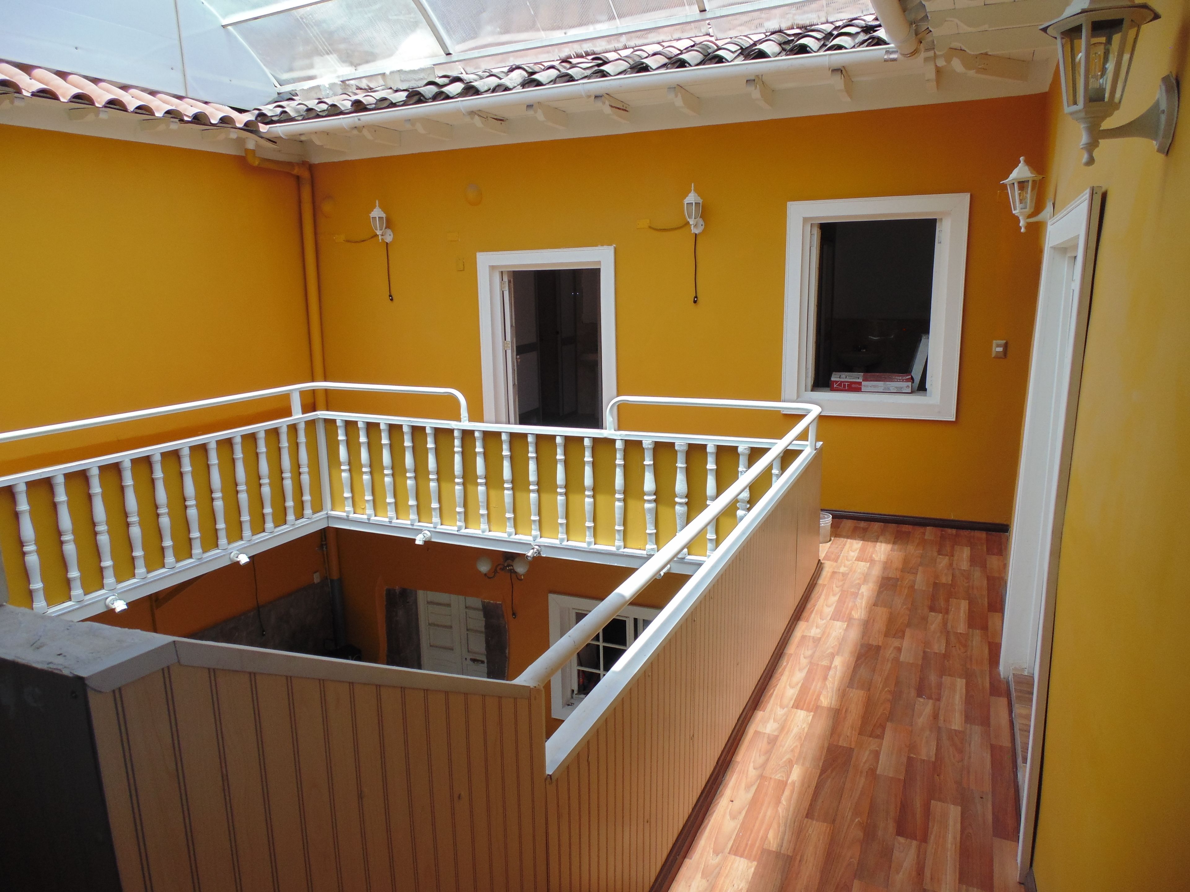 A balcony with a white railing, yellow walls, and wooden flooring.
