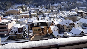 Une ville enneigée, avec des bâtiments traditionnels et une chaîne de montagnes en arrière-plan.