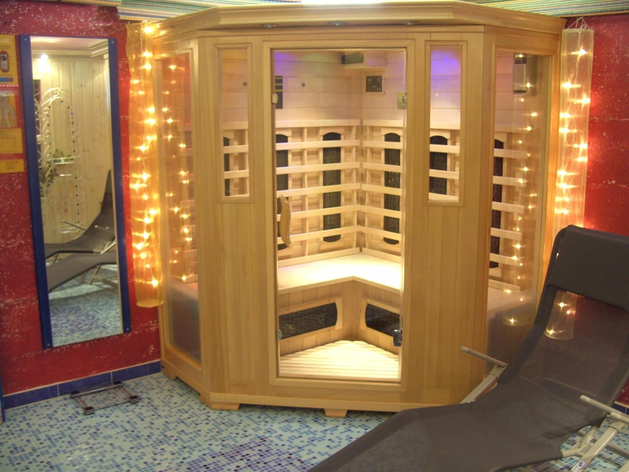 Eine Sauna mit Holzbau, einer Sitzbank und einem Spiegel an der Wand.