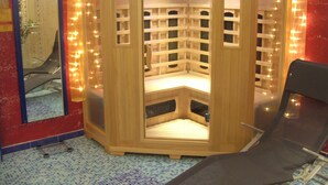 Un sauna avec une structure en bois, un banc et un miroir au mur.