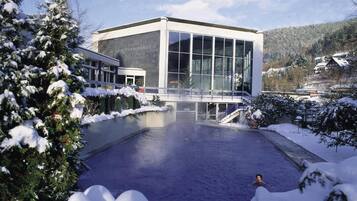 Ein modernes Gebäude mit großen Fenstern, einem Pool und verschneiter Umgebung.