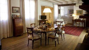 A dining area with a wooden table, chairs, a television, and a red rug. - B&B Casa Fabbris (Sandrigo)