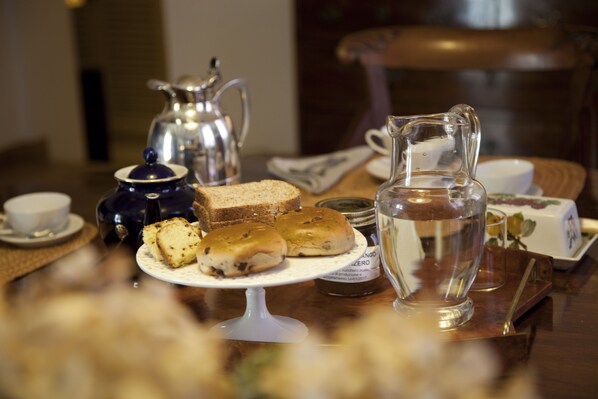 Una mesa con una jarrón, tetera, tazas y pasteles.