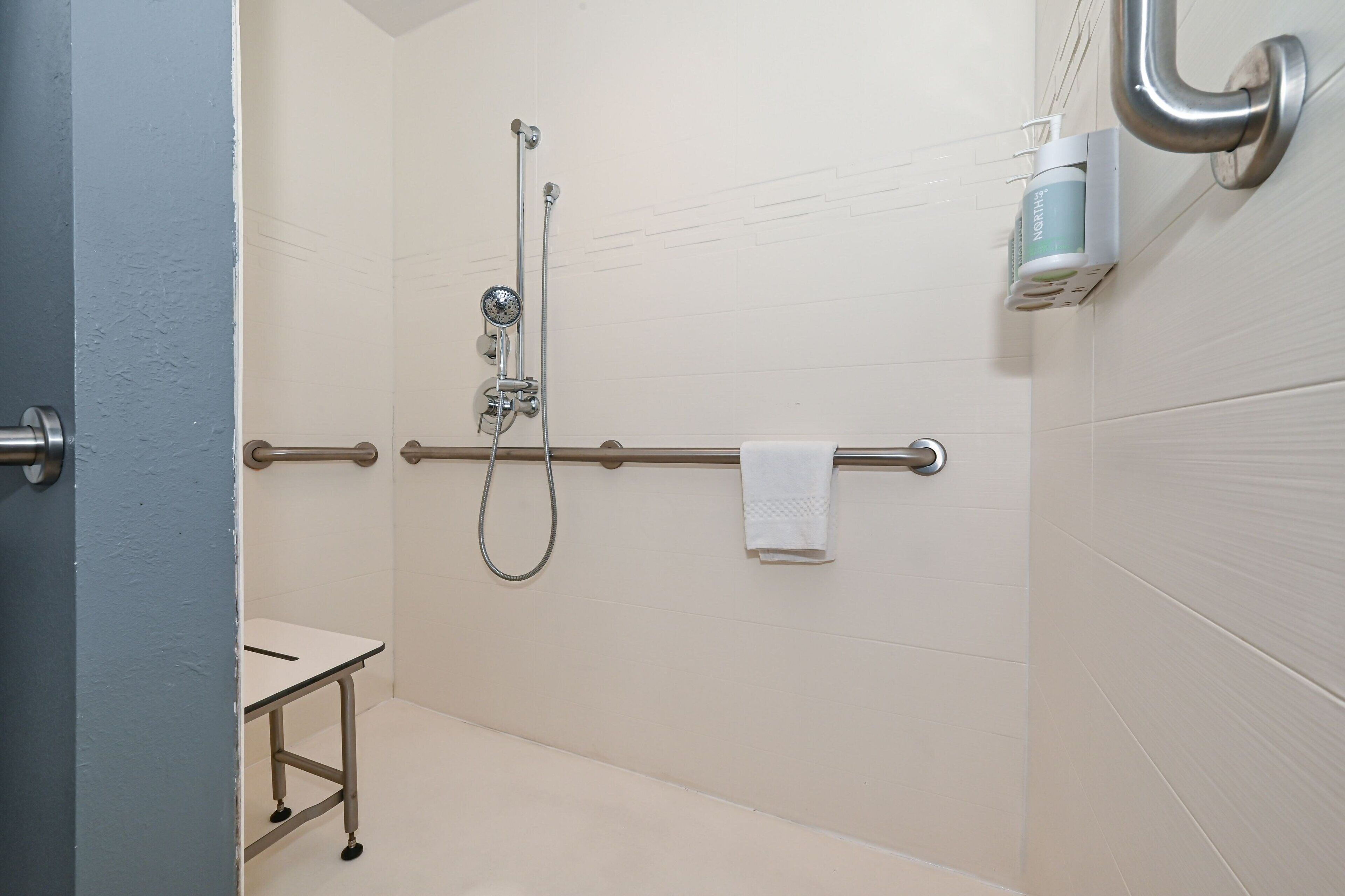 Une salle de bain avec une douche, un porte-serviettes et une petite table.