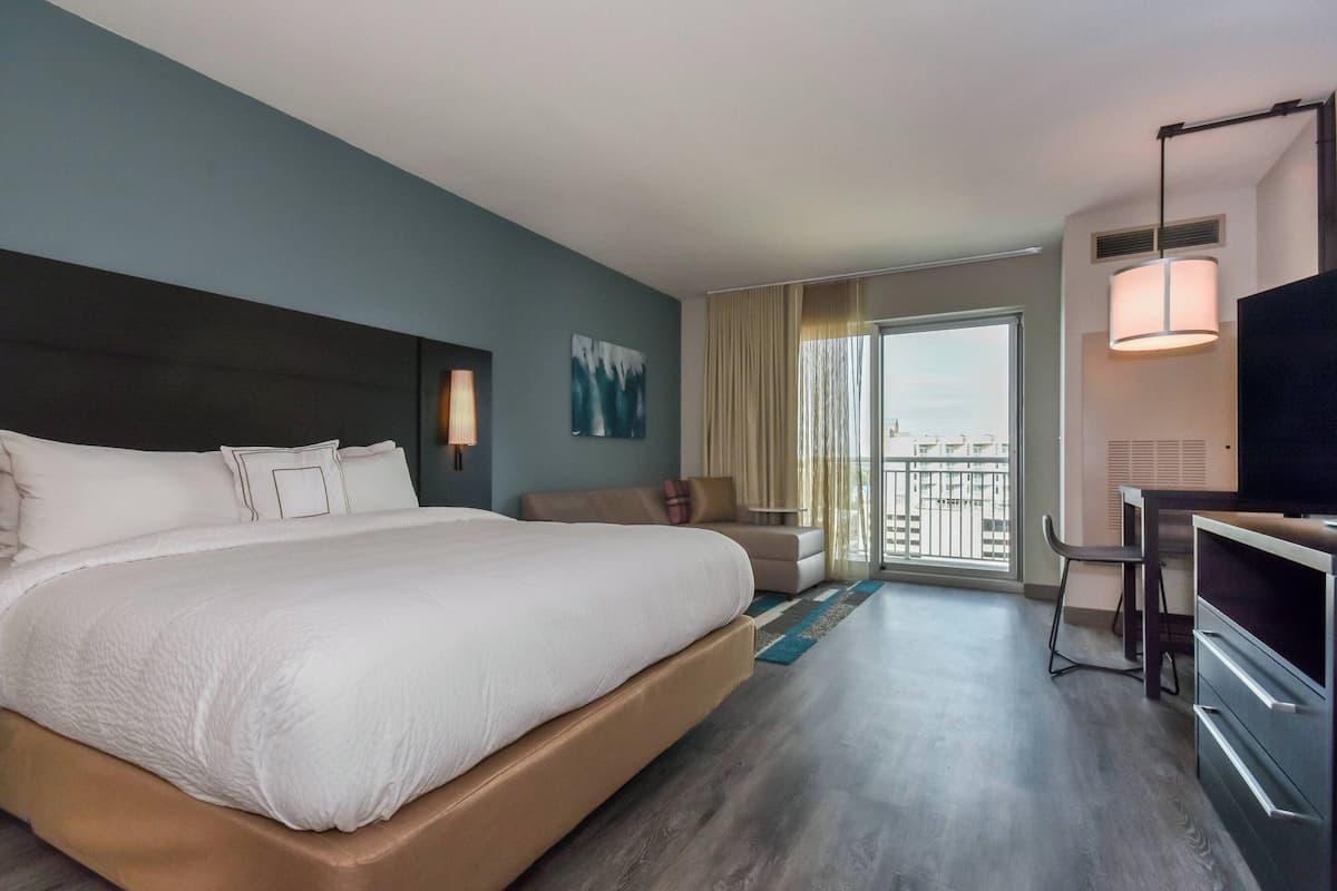 A hotel room with a large bed, a sofa, a desk, and a TV.