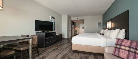 Een hotelkamer met een bed, een bureau, een televisie en een kitchenette.