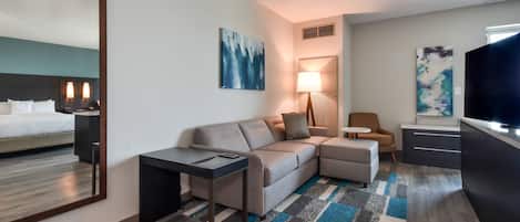 Ett modernt hotellrum med en bäddsoffa, ett litet bord, en TV och konstverk på väggarna.