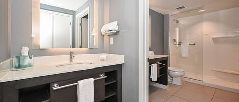 A modern bathroom with a large mirror, a sink, a toilet, and a shower area.