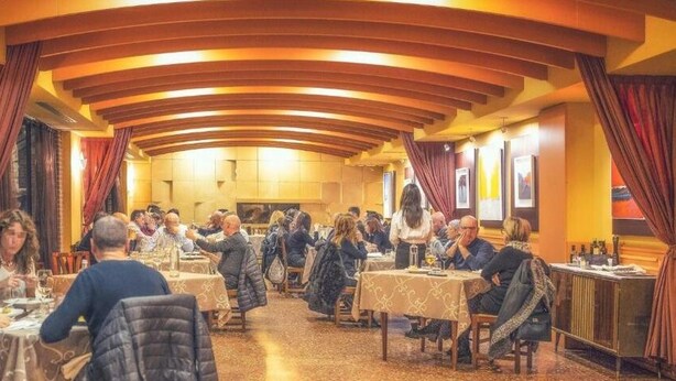 A restaurant with round tables and red curtains, featuring a warm interior and a high ceiling. - Hotel Ristorante Due Platani (Cornedo Vicentino)