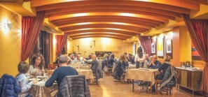A restaurant with round tables and red curtains, featuring a warm interior and a high ceiling. - Hotel Ristorante Due Platani (Cornedo Vicentino)