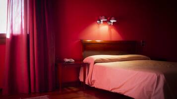 Une chambre d’hôtel avec une tête de lit en bois, une table de chevet avec un téléphone et un mur rouge.