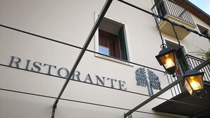 A building with a sign that reads "RISTORANTE" and some Chinese characters. There are outdoor lights and a camera on the wall. - Hotel Ristorante Due Platani (Cornedo Vicentino)