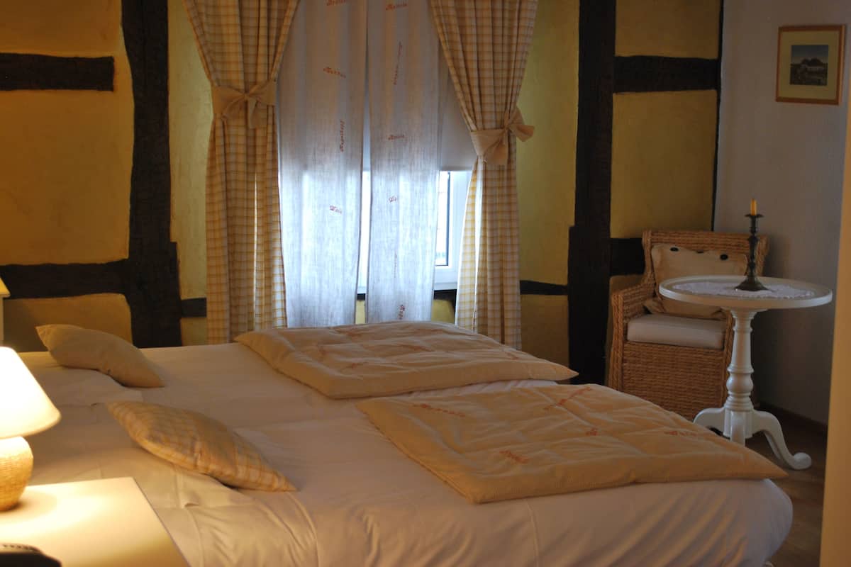A bedroom with two beds, a bedside table, a chair, and a small table with a candle.