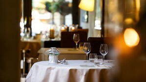 Una mesa vacía con mantel blanco, candelabro de vidrio y copas de vino.