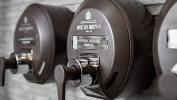 Dispensador fixado na parede com etiqueta para shampoo Molton Brown.