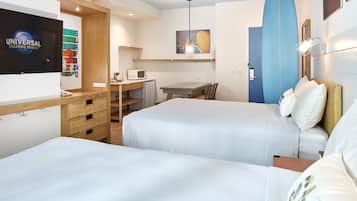 A hotel room with two beds, a TV displaying 'Universal Orlando Resort', a surfboard, and a small kitchenette.