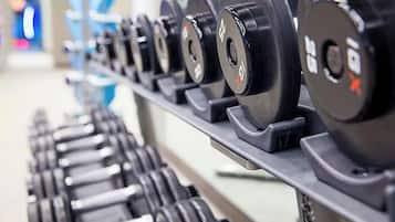 A row of black dumbbells with weight markings on a rack.