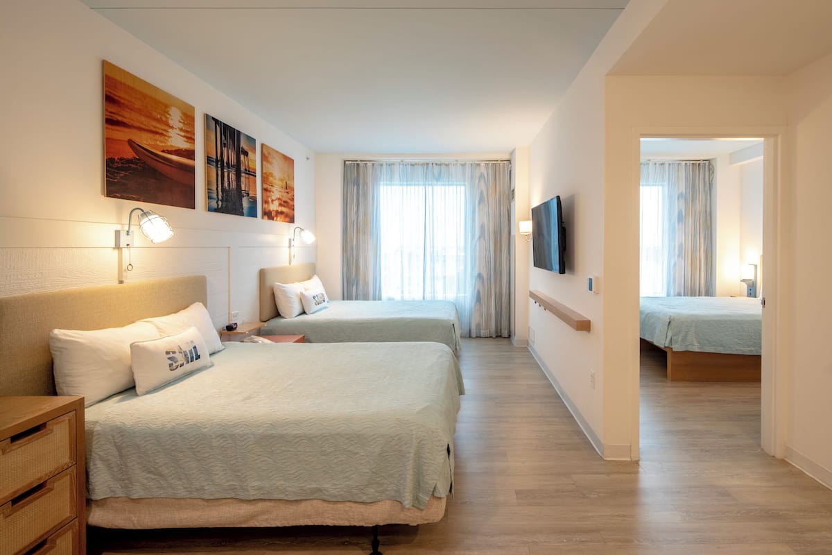 Ein Hotelzimmer mit zwei Betten, einem Fernseher und Bildern an den Wänden.