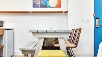 Eine moderne Küche mit einem weißen Kühlschrank, einem Holzkasten, einem Esstisch mit Stühlen und einer Hängeleuchte.