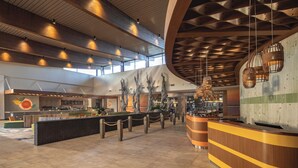 A spacious lobby with a central reception desk, a large mural, and a modern ceiling design. - Universal's Endless Summer Resort - Dockside Inn and Suites (Orlando)
