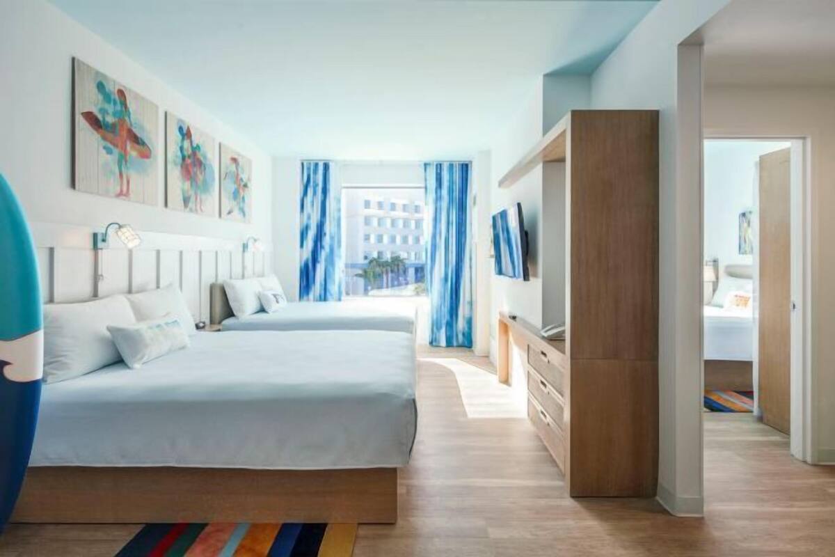 Ein modernes Schlafzimmer mit einem großen Bett, einem Fernseher und Kunstwerken an der Wand.