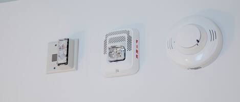Three smoke detectors mounted on a plain wall.