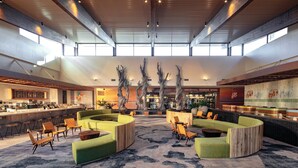 A spacious lobby with a high ceiling, seating areas, and a bar. - Universal's Endless Summer Resort - Dockside Inn and Suites (Orlando)