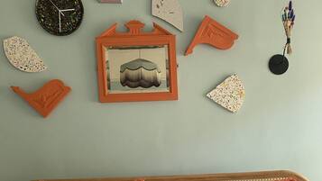 Un lit avec des oreillers de couleur turquoise et une tête de lit en bois, une horloge et divers éléments de décoration murale, notamment un tableau encadré et des formes géométriques.