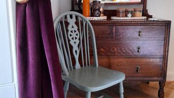 A room with a wooden dresser, a chair, and a mirror.