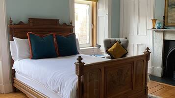 A bedroom with a large bed, a wooden headboard, a patterned rug, and a fireplace.