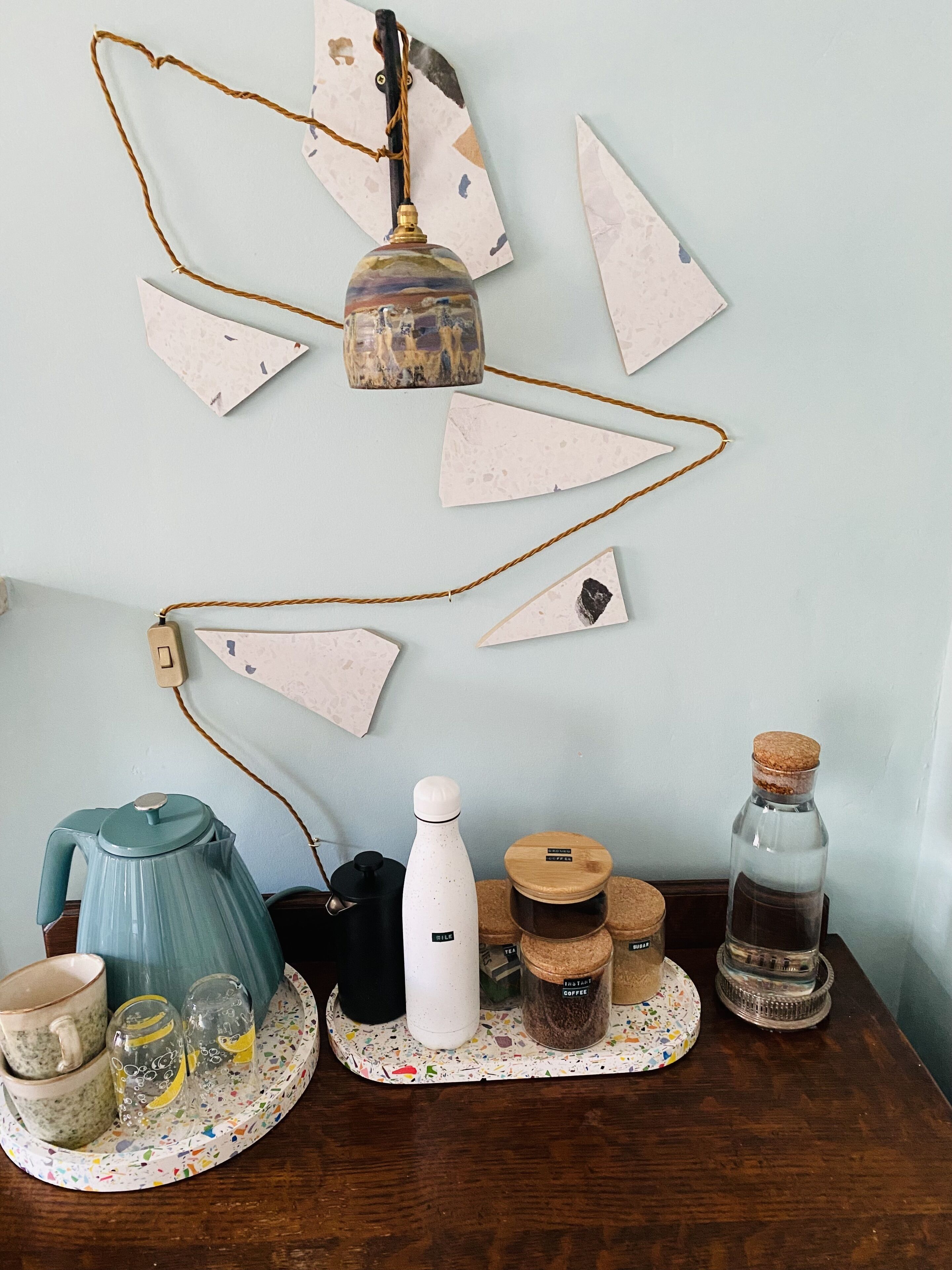 A kitchen counter with a coffee maker, kettle, and jars.