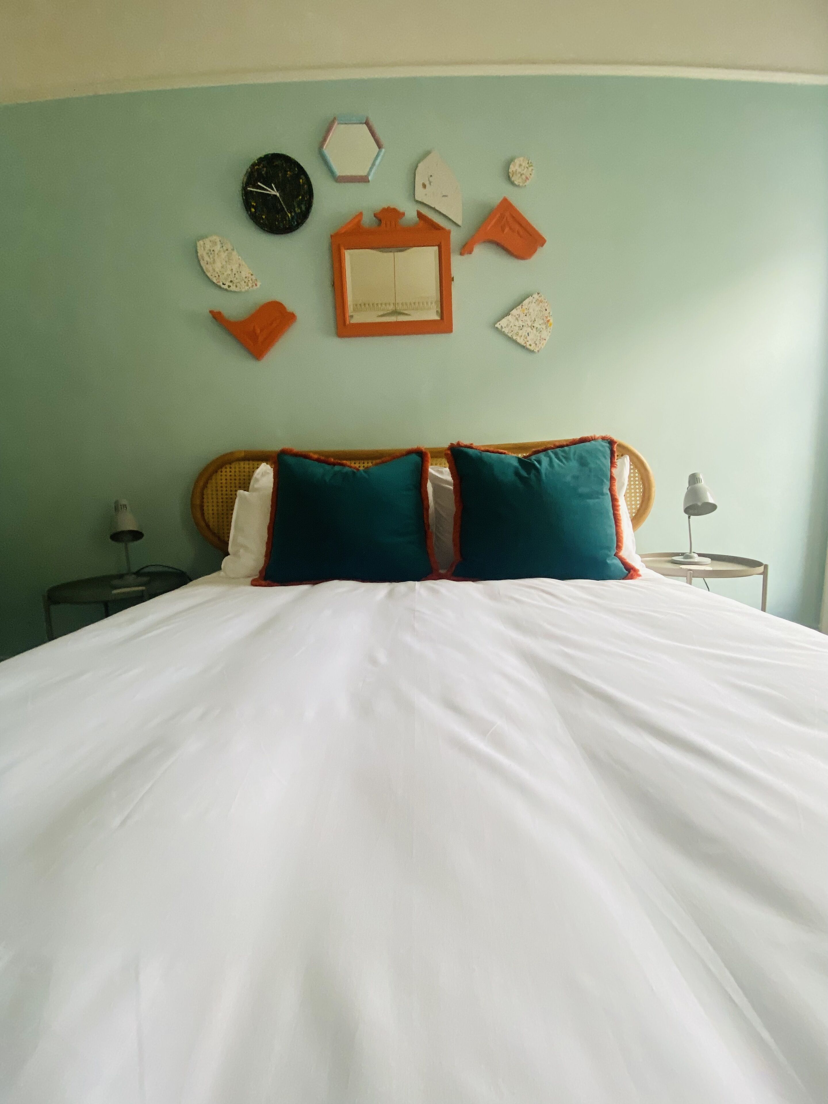 A bed with white bedding, two teal pillows, and a wooden headboard.