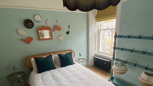 A bedroom with a bed, a window with a view, a radiator, and a wall with decorative items. - Ben A'an House (Callander)