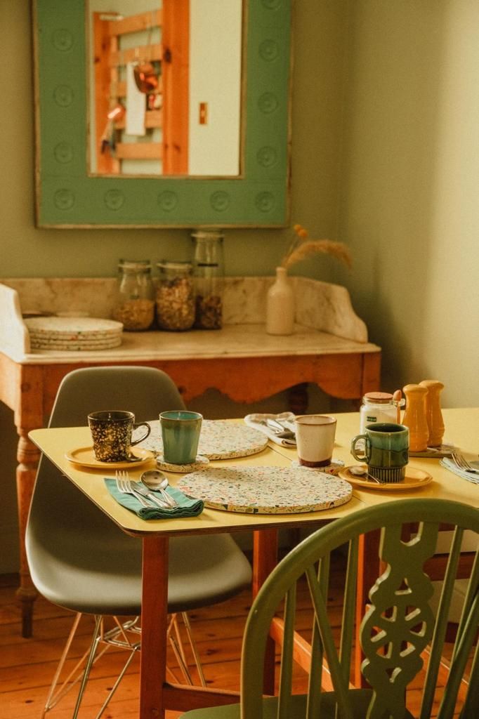 Een eetgedeelte met een tafel voor twee, een stoel en een spiegel aan de muur.