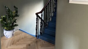 A staircase with a wooden floor, a potted plant, and a framed botanical illustration on the wall. - Ben A'an House (Callander)