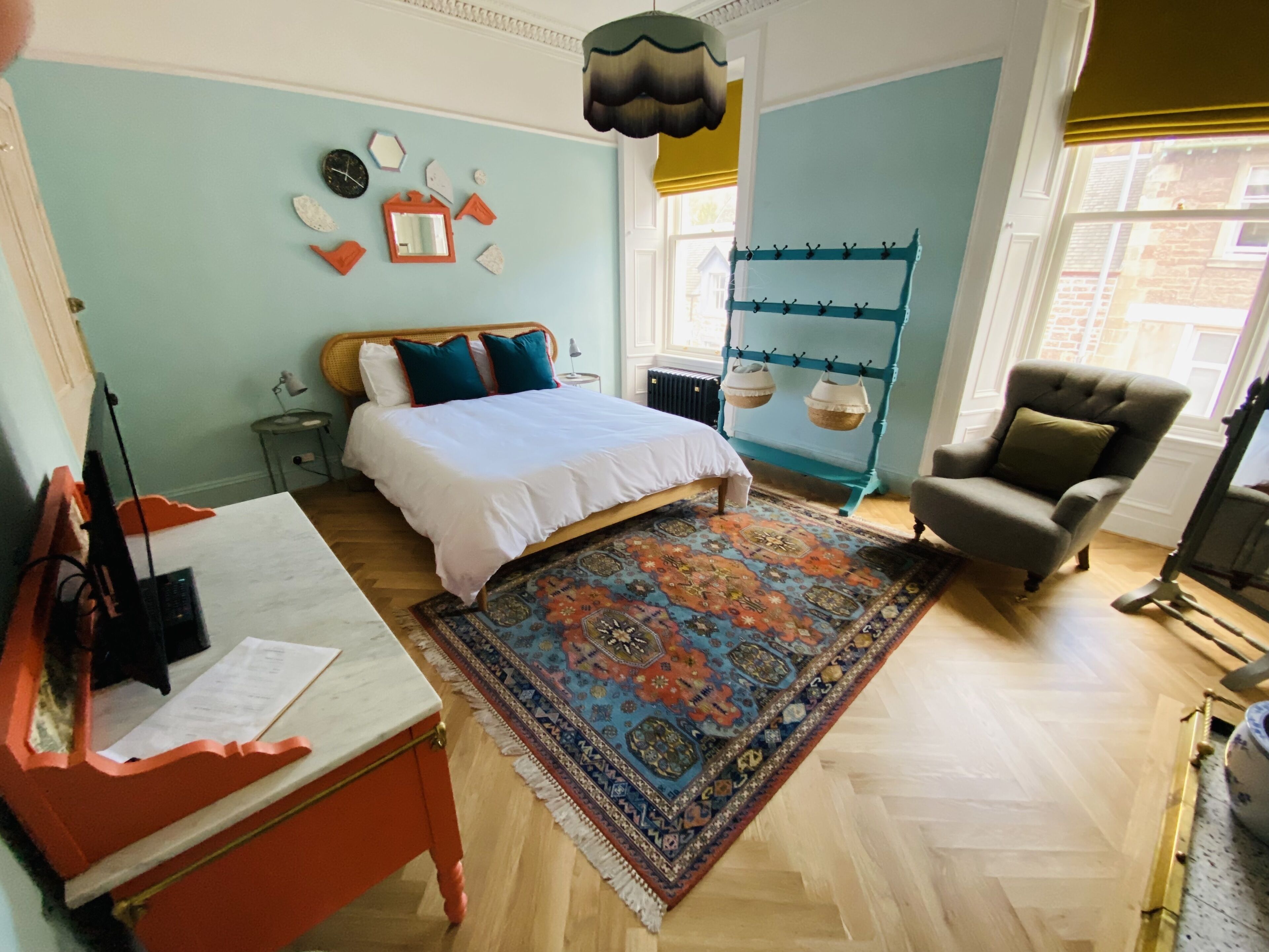Un dormitorio con cama, escritorio, silla, alfombra y ventana con vistas.