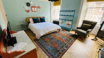Un dormitorio con cama, escritorio, silla, alfombra y ventana con vistas.