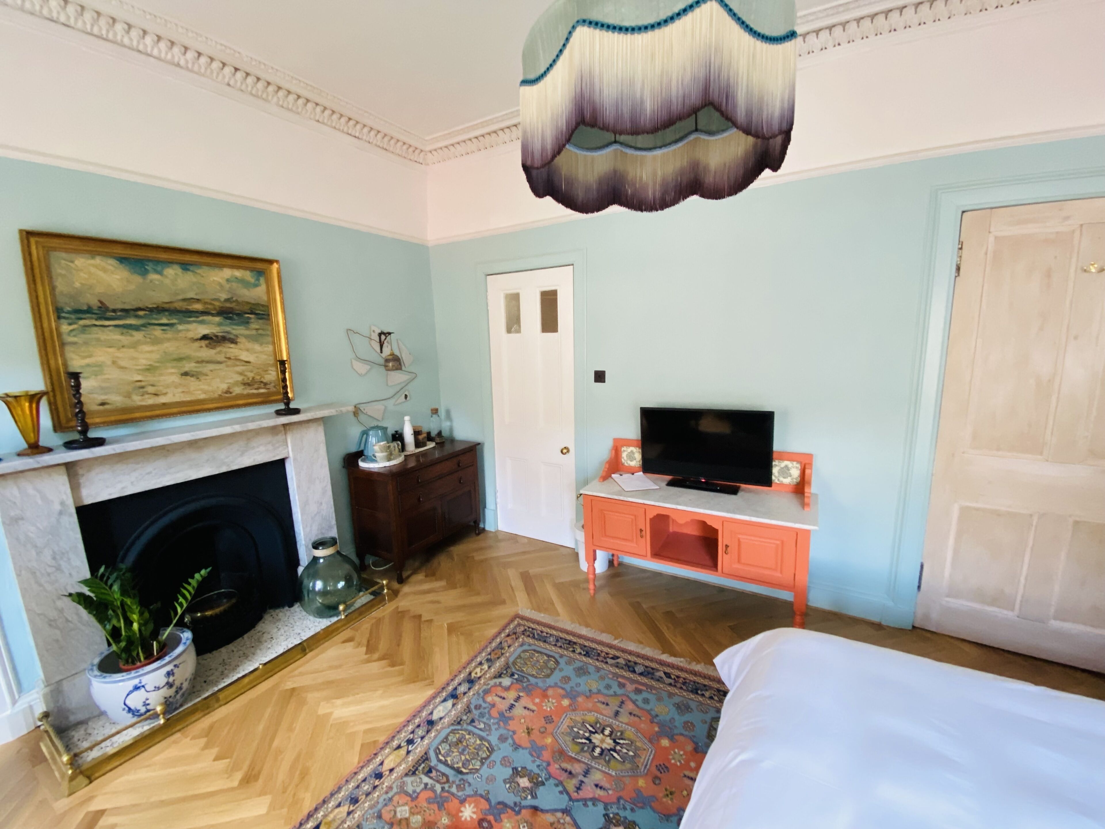 A bedroom with a fireplace, a television on a stand, a bed, and a decorative rug.