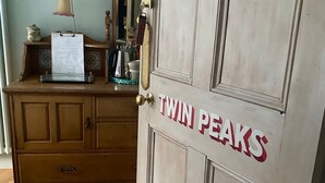 A room with a wooden dresser, a desk with a lamp, and a door labeled "TWIN PEAKS". - Ben A'an House (Callander)