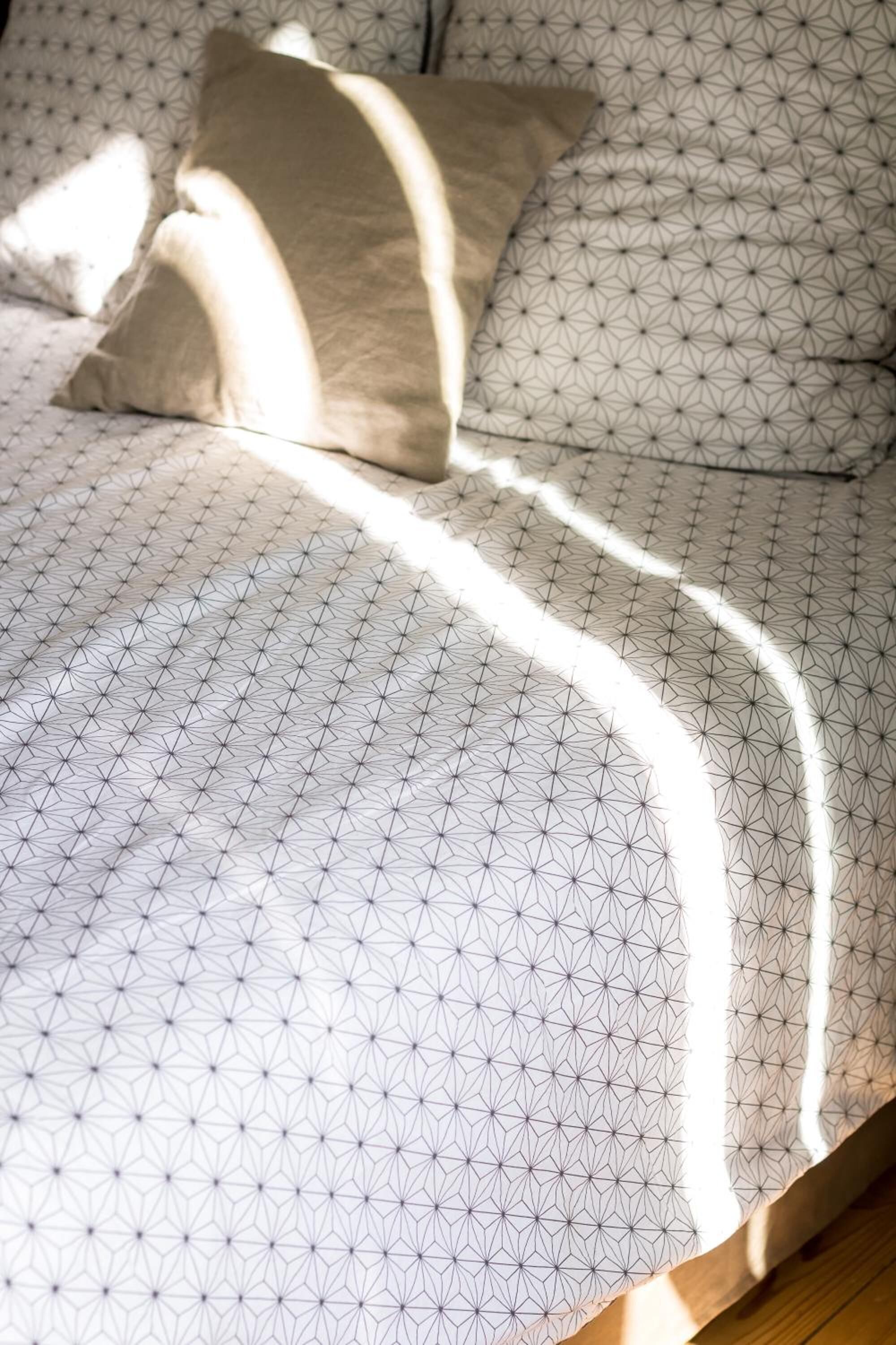 Una cama con edredón y almohadas de estampado geométrico.
