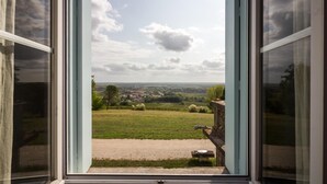 Vista desde una ventana con cielo despejado y un paisaje de campos y edificios.