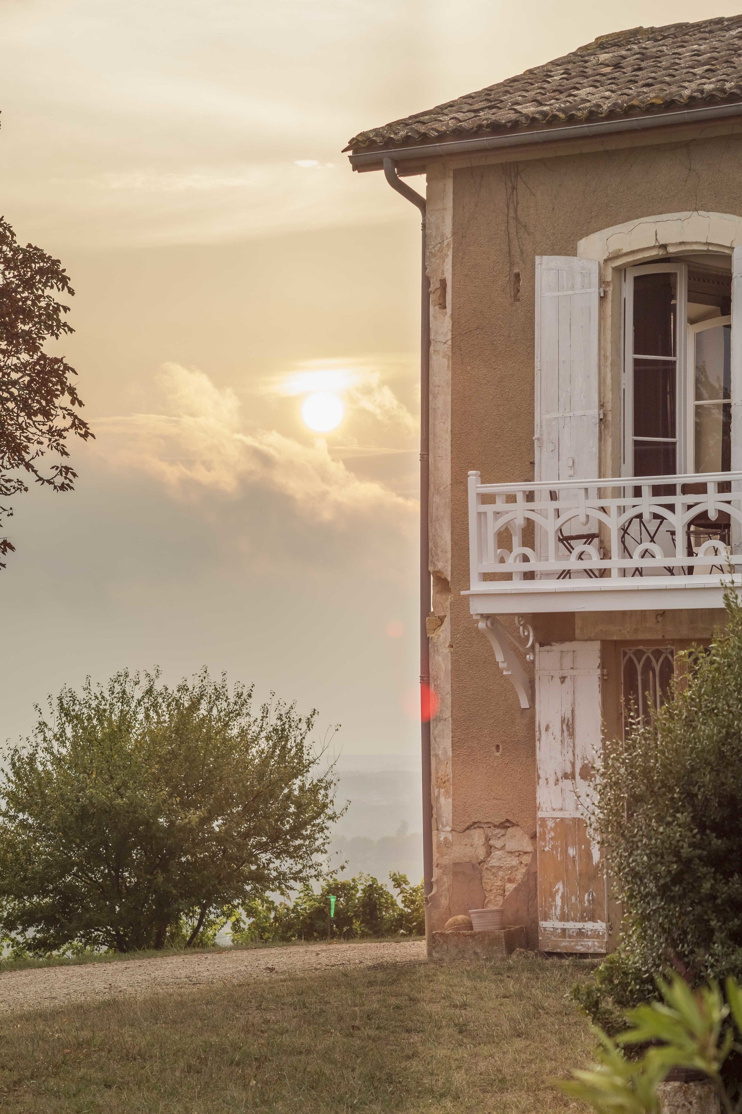 Un bâtiment rustique doté d’un balcon, d’une fenêtre avec des volets et offrant une vue sur le ciel.