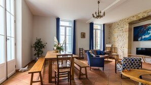 Un salón amplio con una mesa de comedor de madera, cortinas azules, un sofá y un televisor.