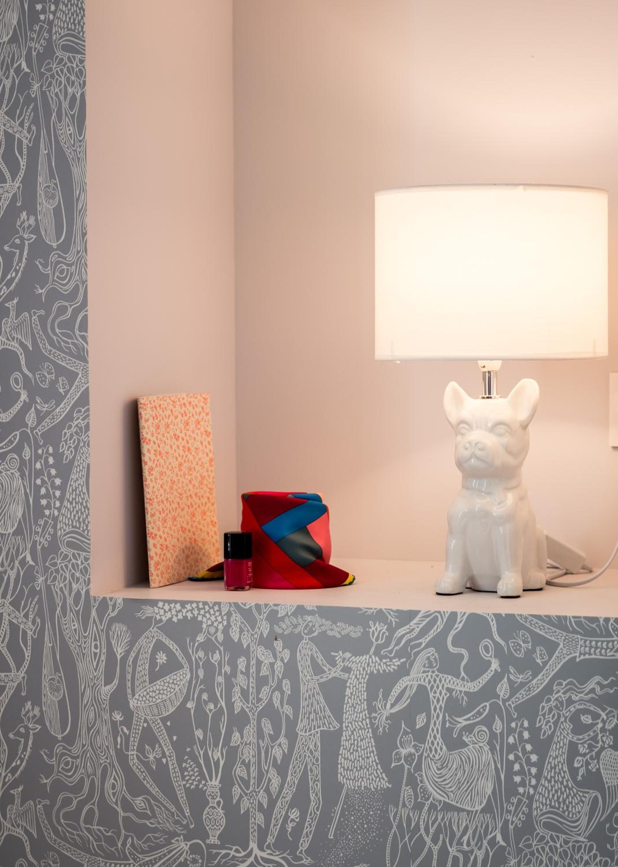 Una mesita de noche con una lámpara, una caja decorativa y una pequeña escultura.
