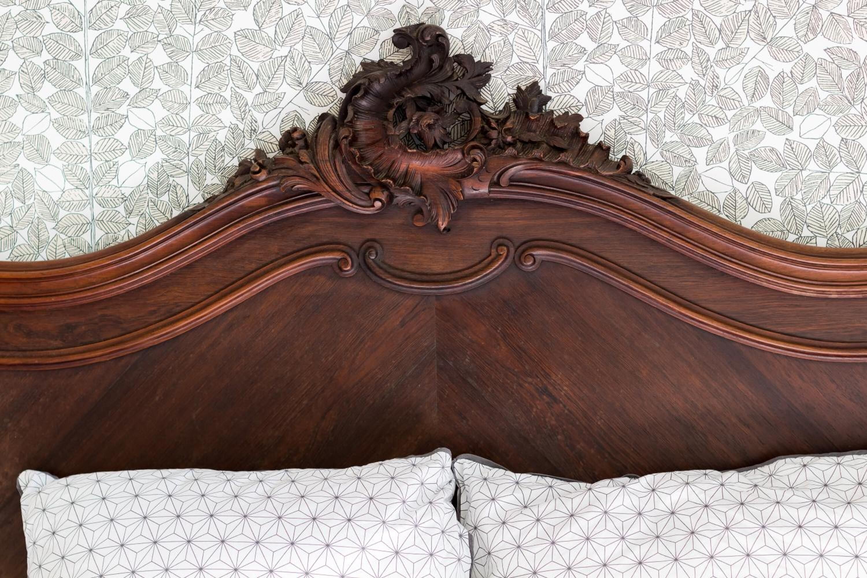 A wooden headboard with intricate carvings and a geometric-patterned pillow.