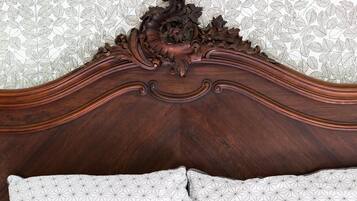 A wooden headboard with intricate carvings and a geometric-patterned pillow.