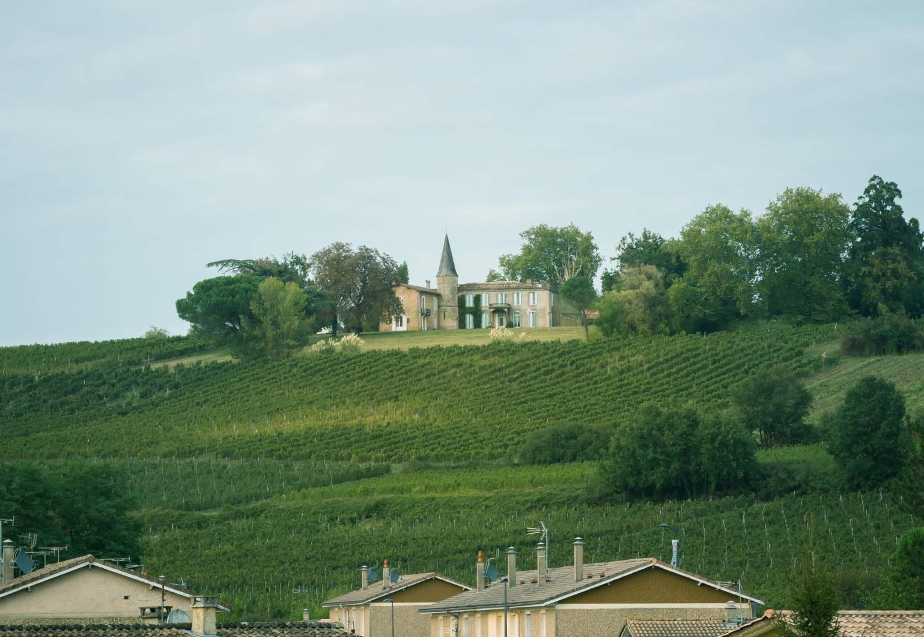 A building with a tower on a hillside, surrounded by greenery and other structures.