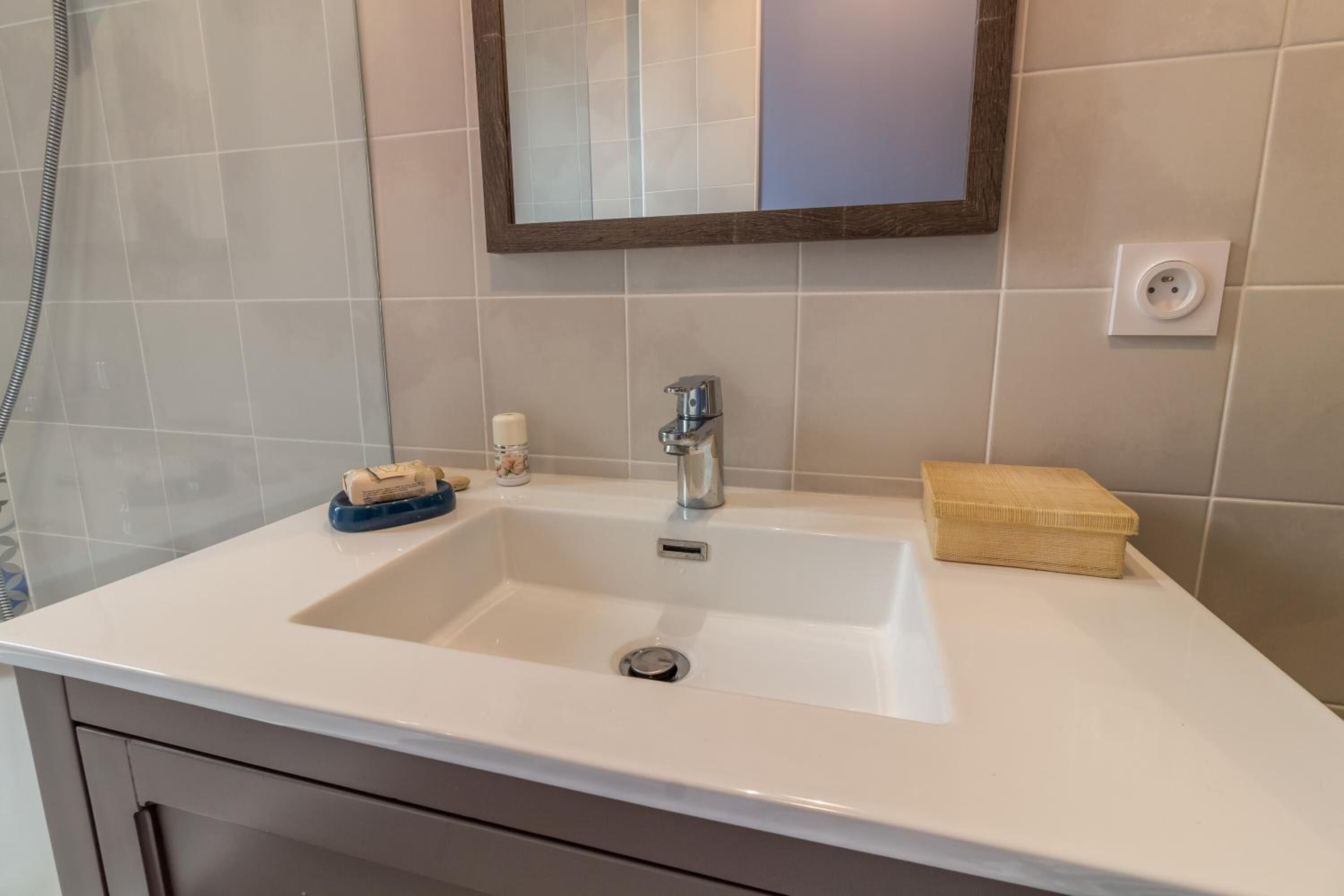 Un baño con un lavamanos blanco, un espejo y un perchero para toallas.