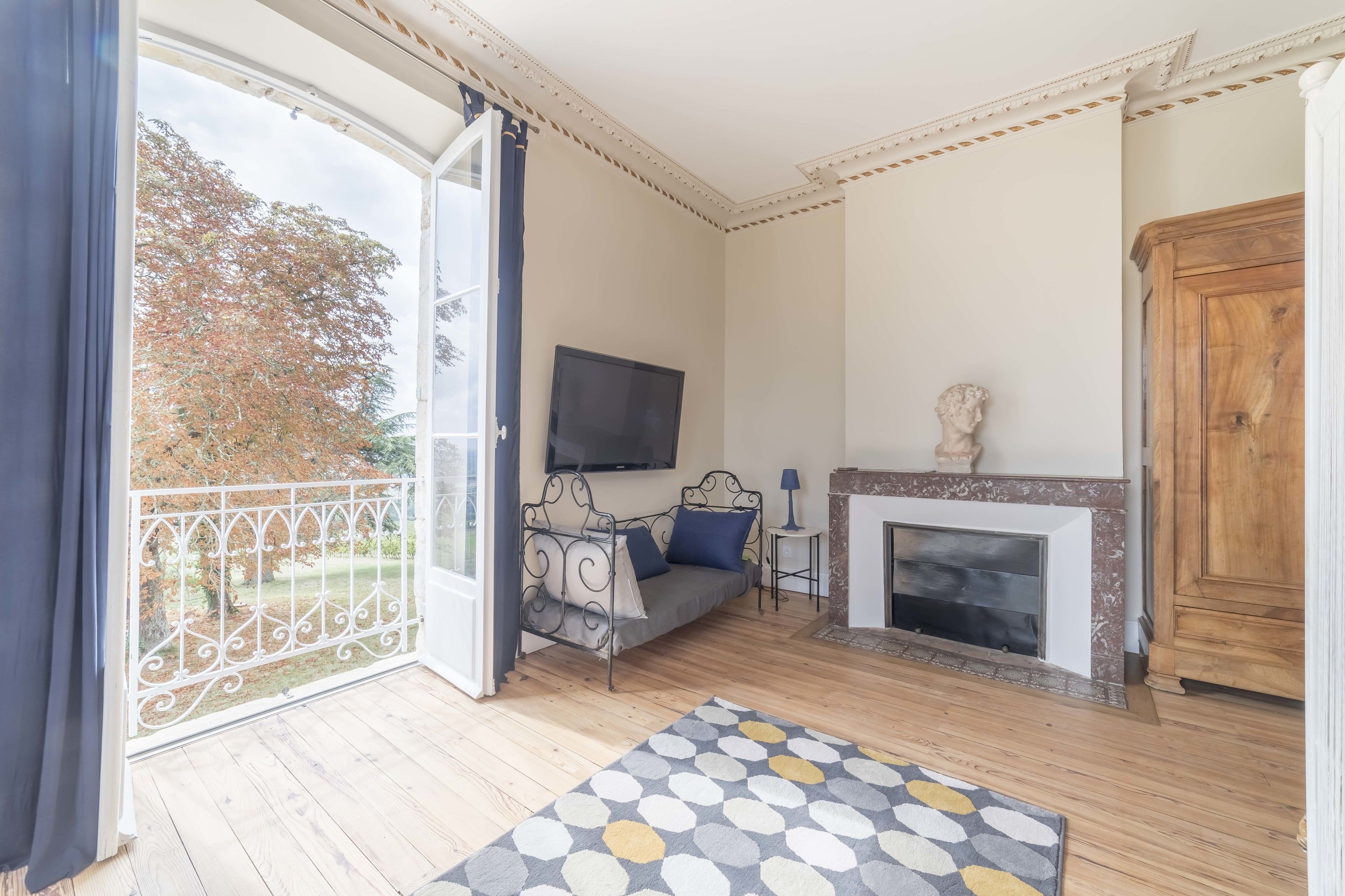 Une pièce comprenant un canapé, une cheminée, un téléviseur et un balcon donnant sur la forêt.