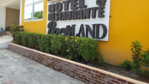 Schild für ein Hotel und Restaurant namens Rockland, mit einem Ziegelpflanzgefäß und Grünpflanzen davor.
